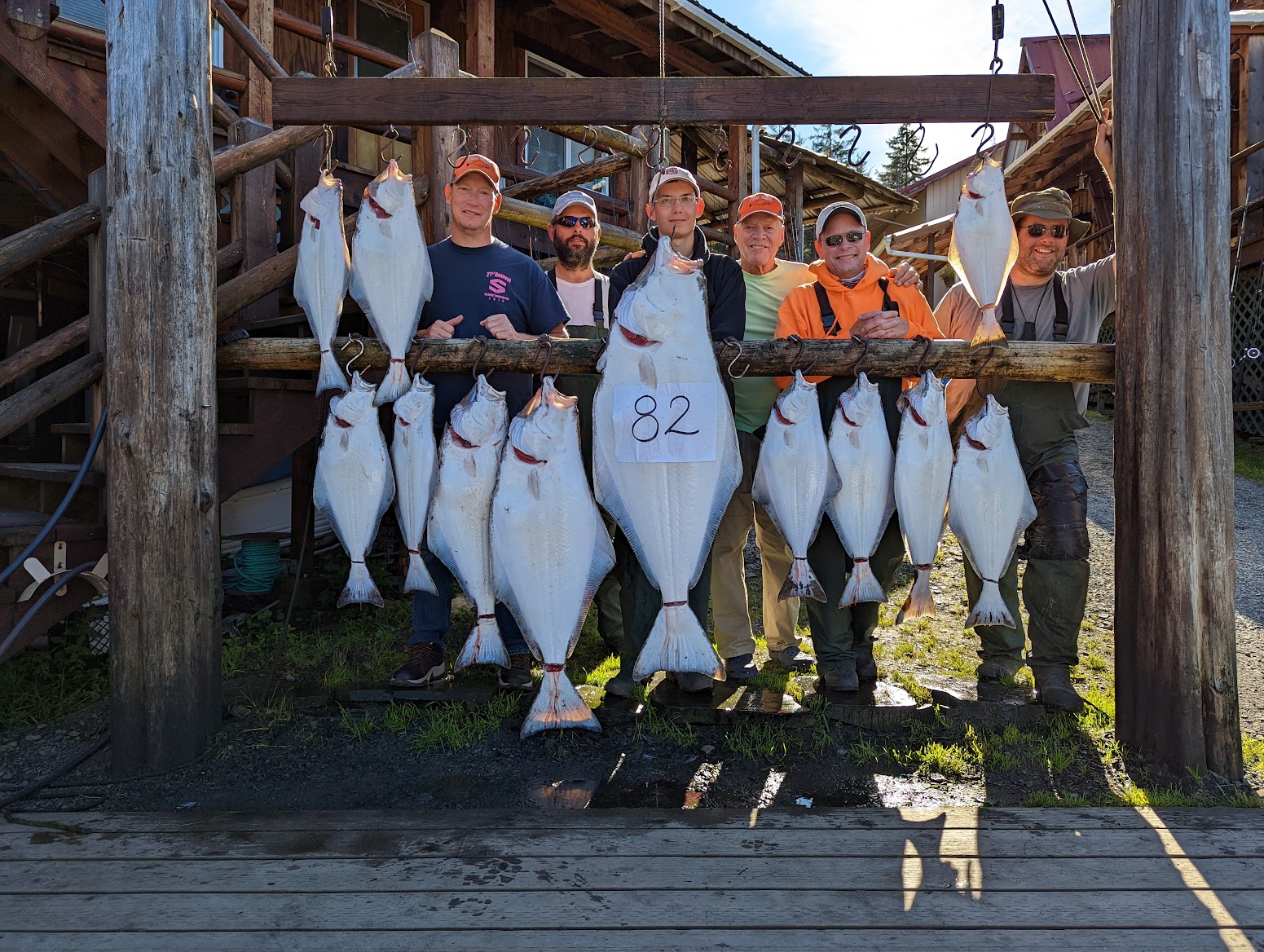 Full crew posing with an impressive halibut catch including an 82-pounder