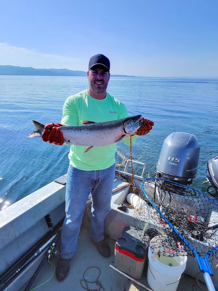 Angler holding a fresh-caught salmon on the boat in Southeast Alaska